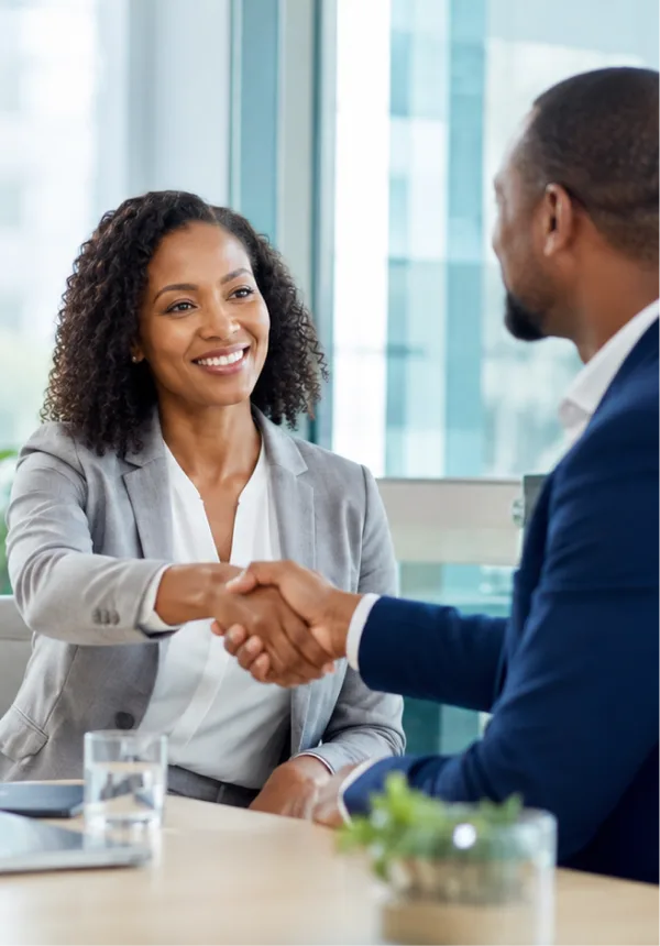 Two professionals shaking hands across a meeting table